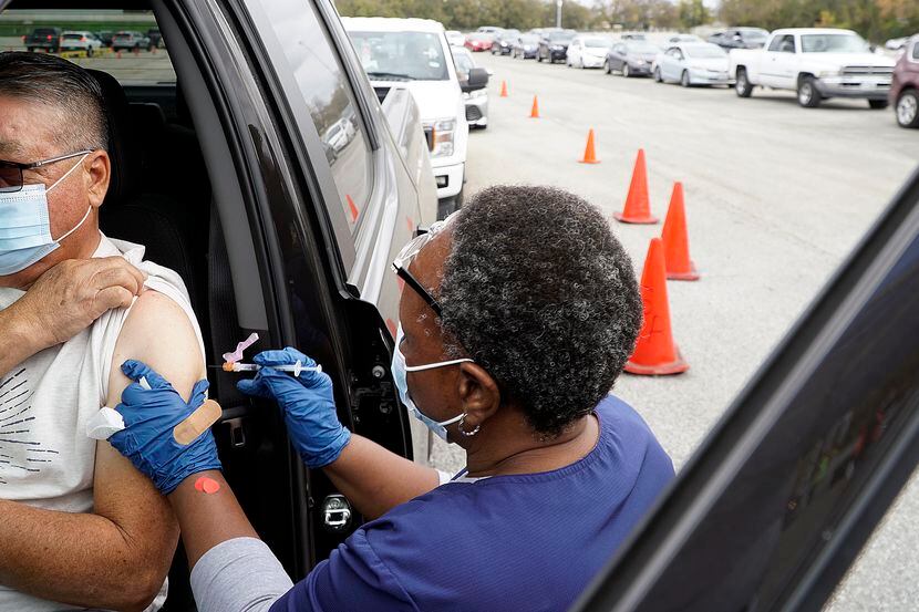 Mary Mbogo gives Victor Rendon a Covid shot at the drive-thru vaccine at Fair Park in...