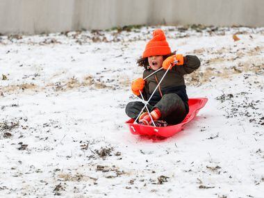 Miles Jarret, 4, slides down the hillside covered by sleet near at White Rock Lake in Dallas...