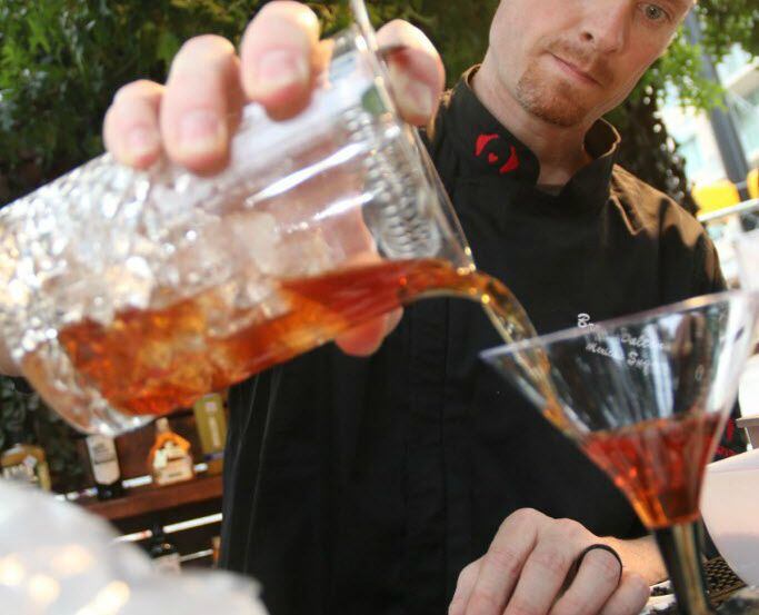 A bartender pours a drink during the 2016 Ultimate Cocktail Experience at Klyde Warren Park.