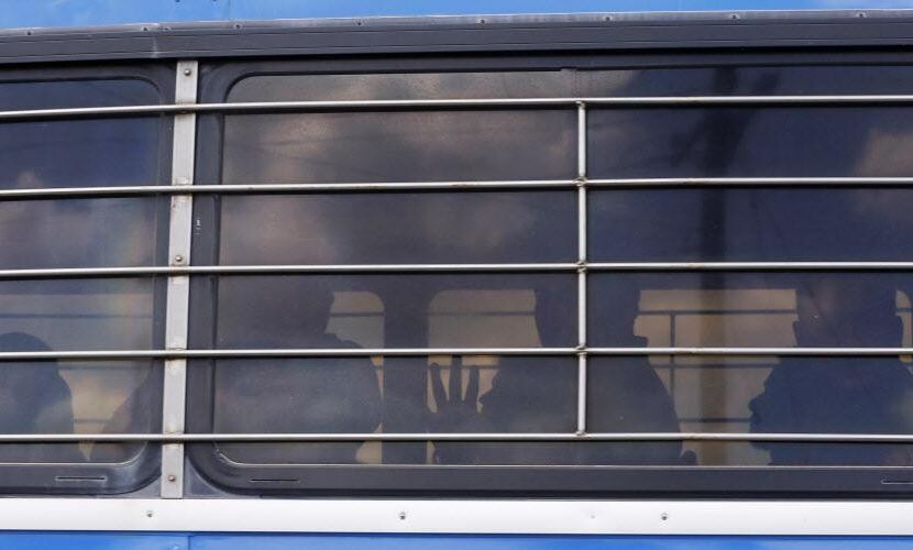  Un trabajador detenido pone su mano en la ventana al interior del autobús que lo llevó a un...