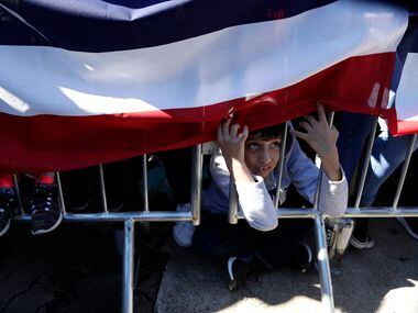A young boy peeks under a banner as he watches former San Antonio Mayor and Housing and...