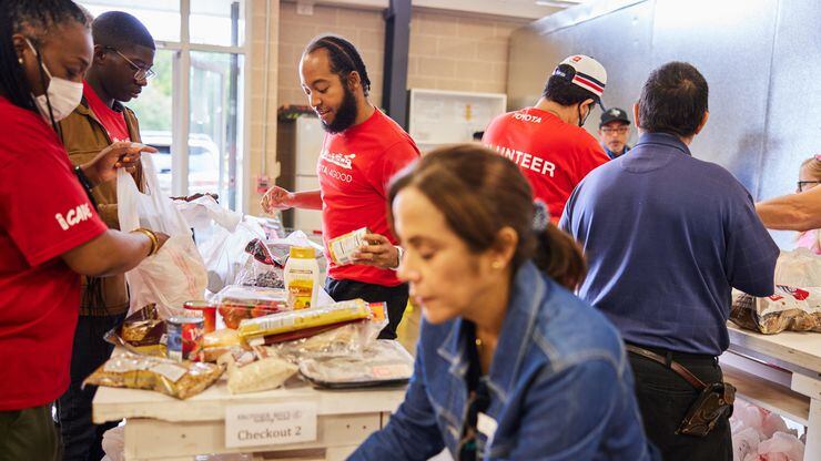 Volunteers in red T-shirts help sort food at a food pantry.