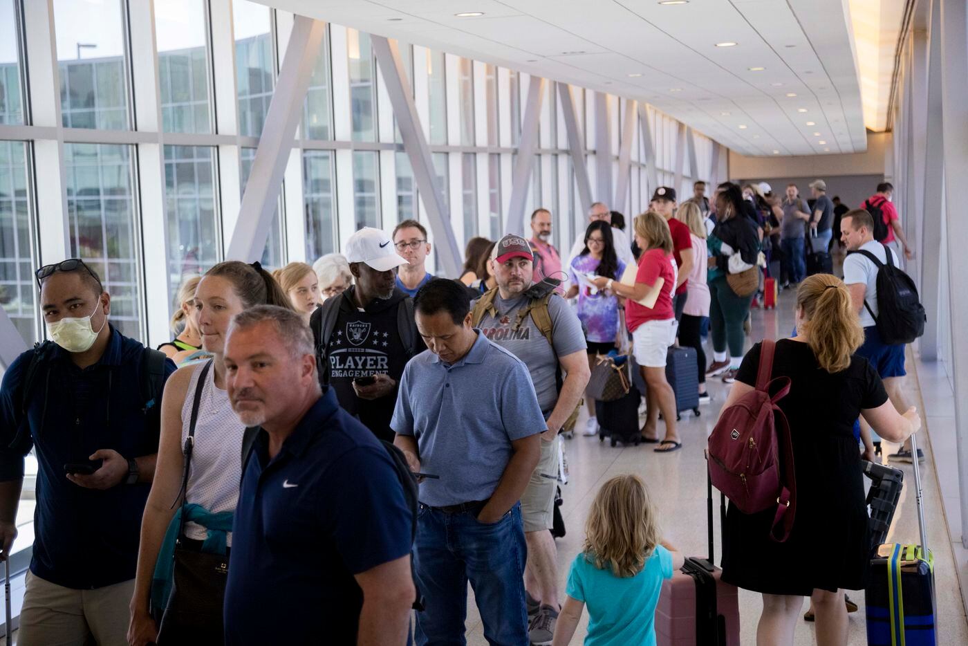 People wait in line to reenter the airport as Dallas police investigate reports of a...