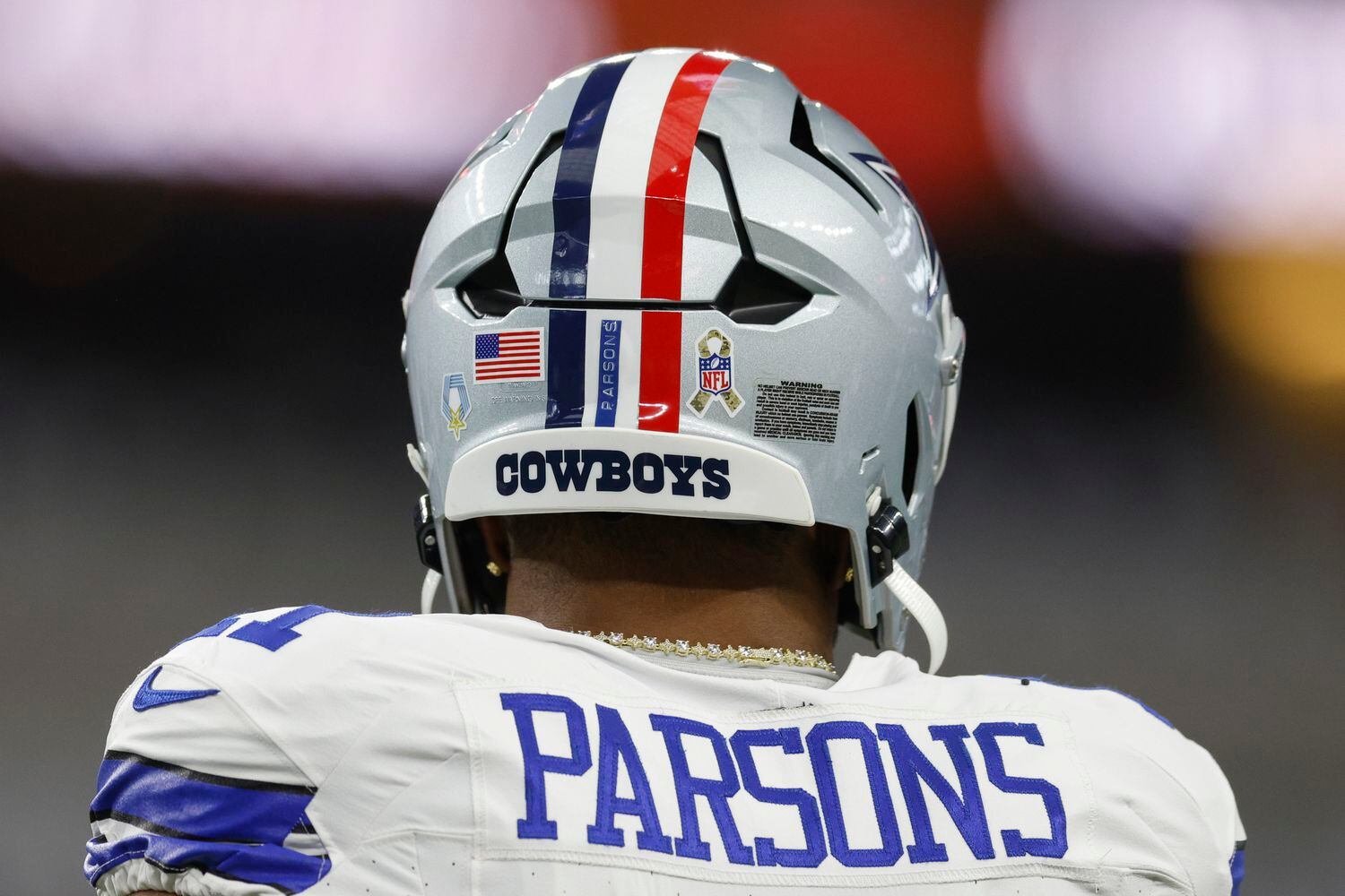 Dallas Cowboys linebacker Micah Parsons wears a helmet featuring a red stripe and ribbon in...