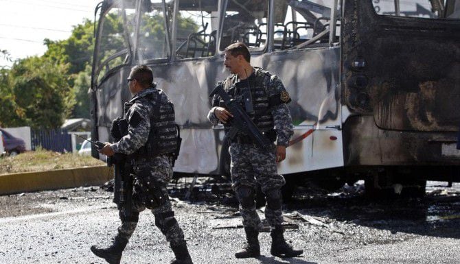 Policías de Jalisco resguardan el lugar donde un autobús fue incendiado por integrantes de...