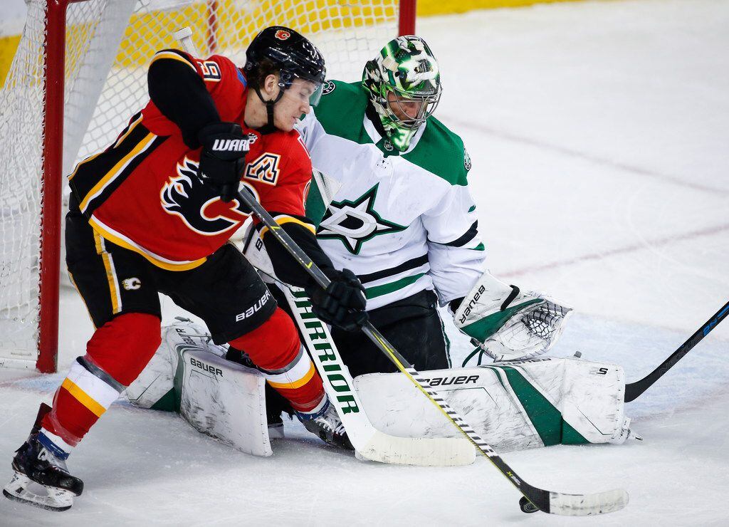 Dallas Stars goalie Ben Bishop, right, blocks the net on Calgary Flames' Matthew Tkachuk...