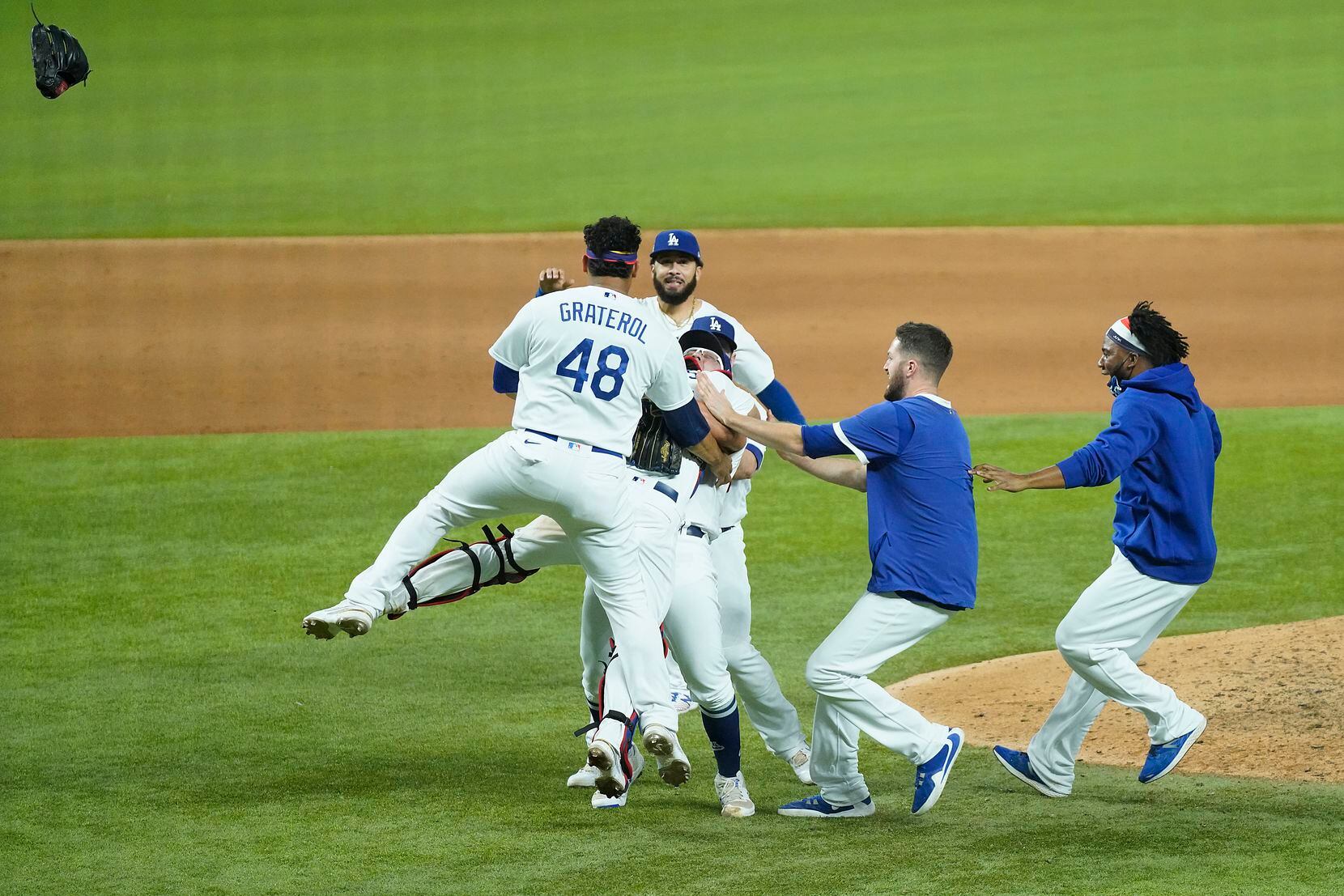 Los Angeles Dodgers players rush to join pitcher Julio Urias and catcher Austin Barnes as...