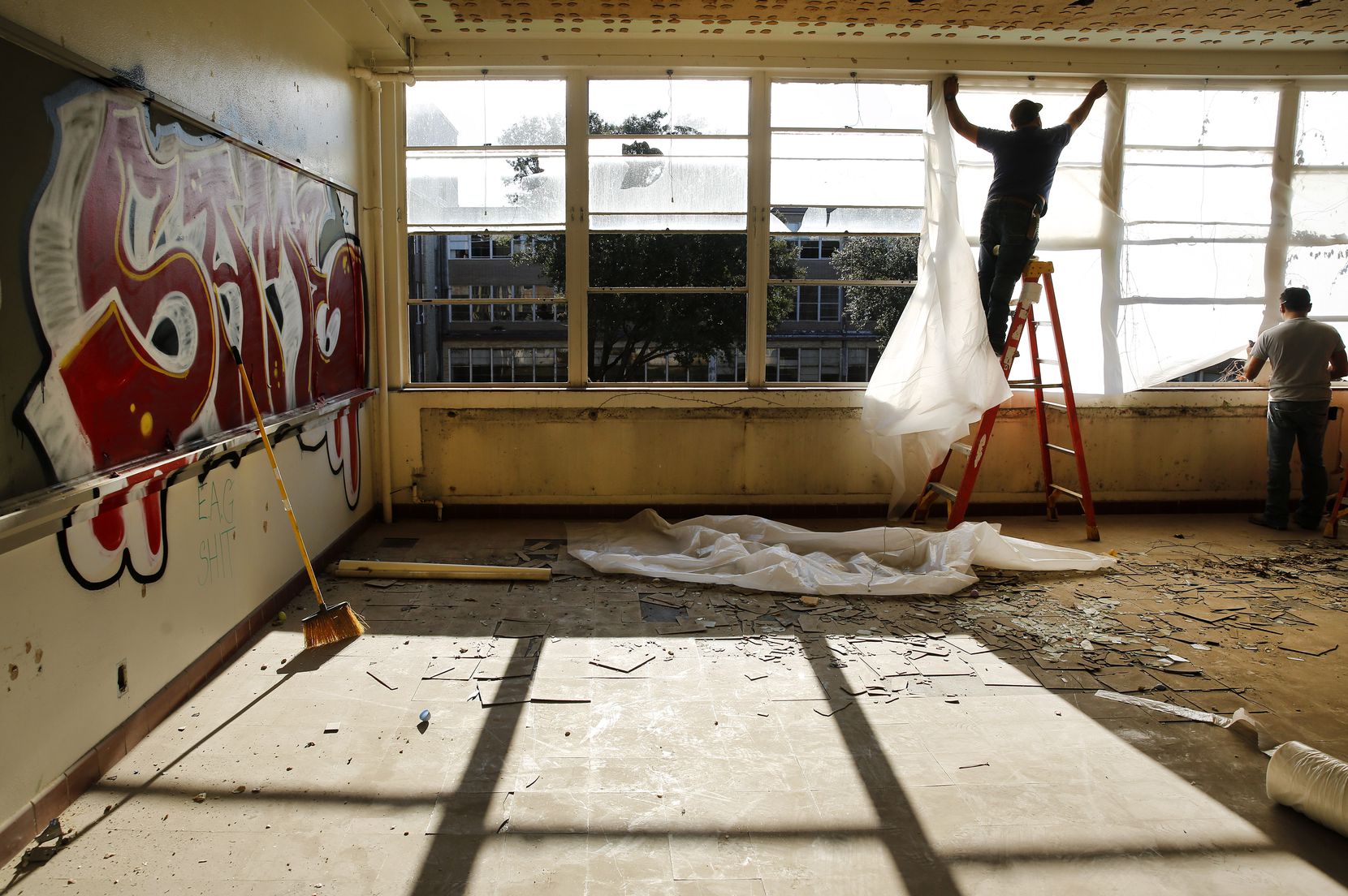 Workers cover broken windows with plastic inside a Pearl C. Anderson Middle Learning Center...