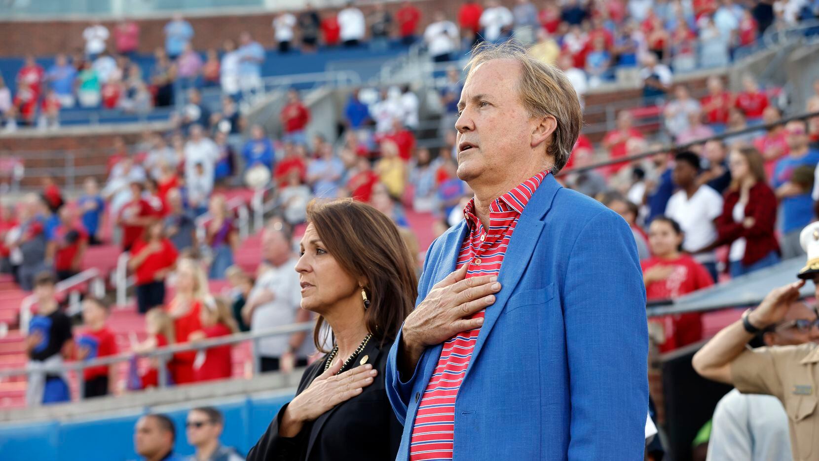 Texas Attorney General Ken Paxton sings the national anthem alongside his wife Angela Paxton...