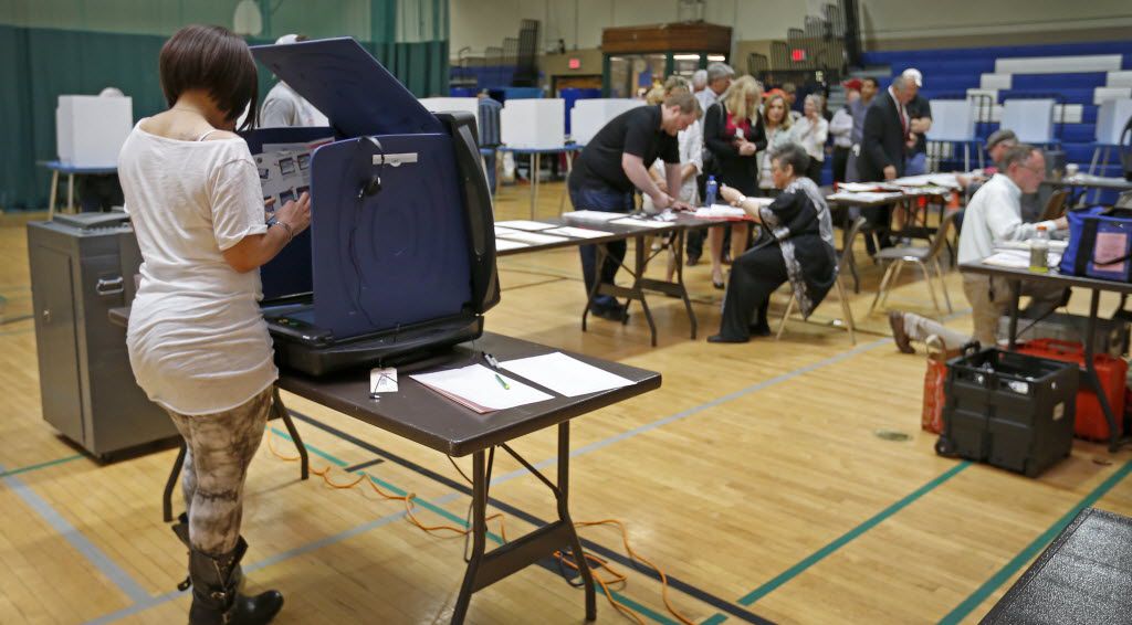 A voter uses an electric voting machine to cast a ballot at Reverchon Park Recreation Center...