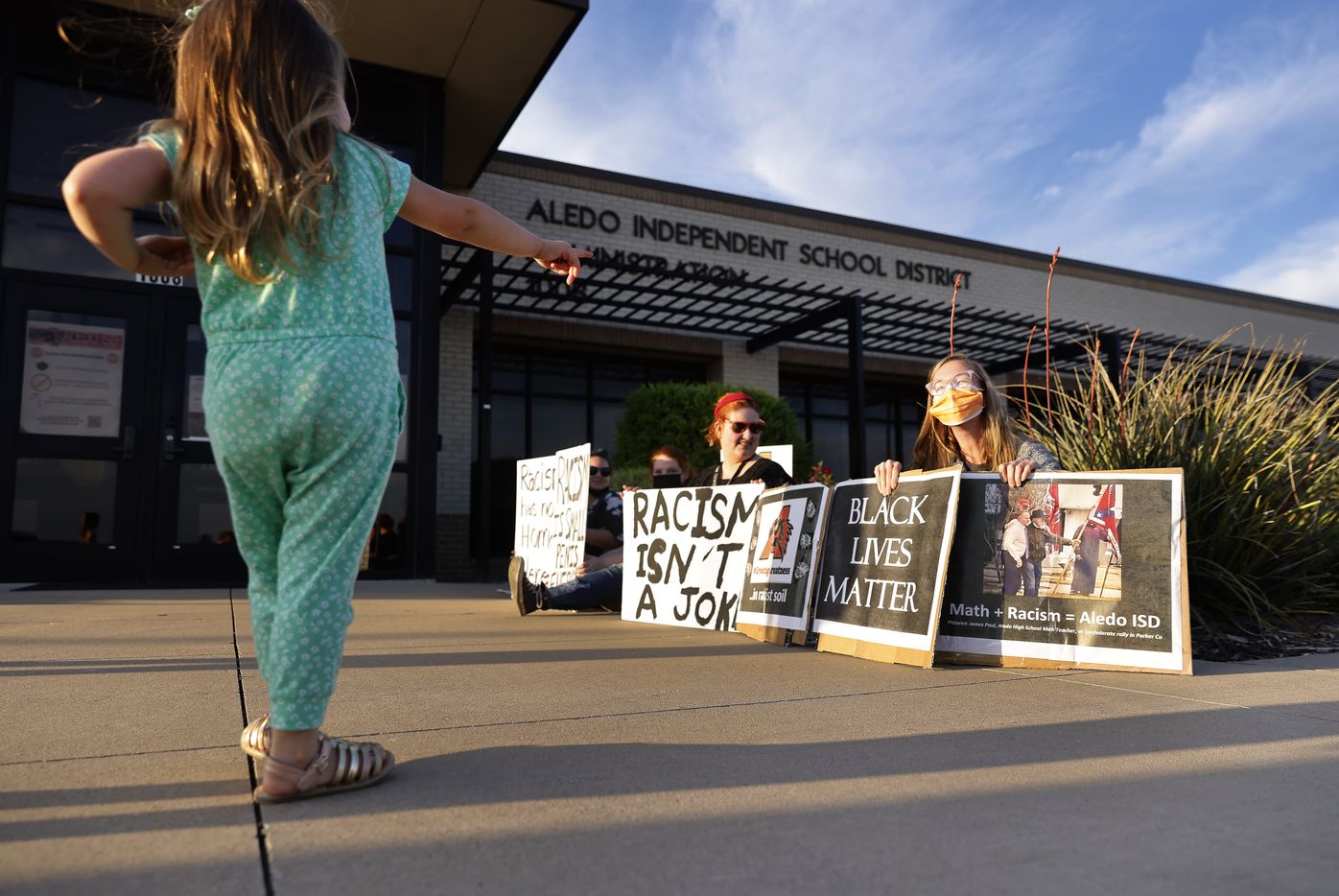Protestors Kayla Miles of Dallas (right) and Emily Overton of Weatherford display signs outside an Aledo ISD school board meeting, Monday, April 19, 2021. Parents and supporters voiced their concerns about racism in the district following a student-led racist Snapchat group with multiple names, including “Slave Trade” and another that included a racial slur. (Tom Fox/The Dallas Morning News)