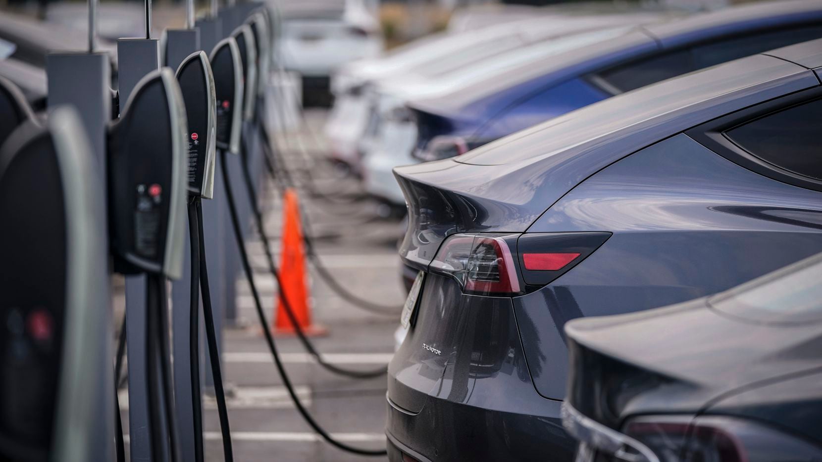 A group of Tesla cars line up at charging stations at a dealership in Littleton, Colo., Aug....