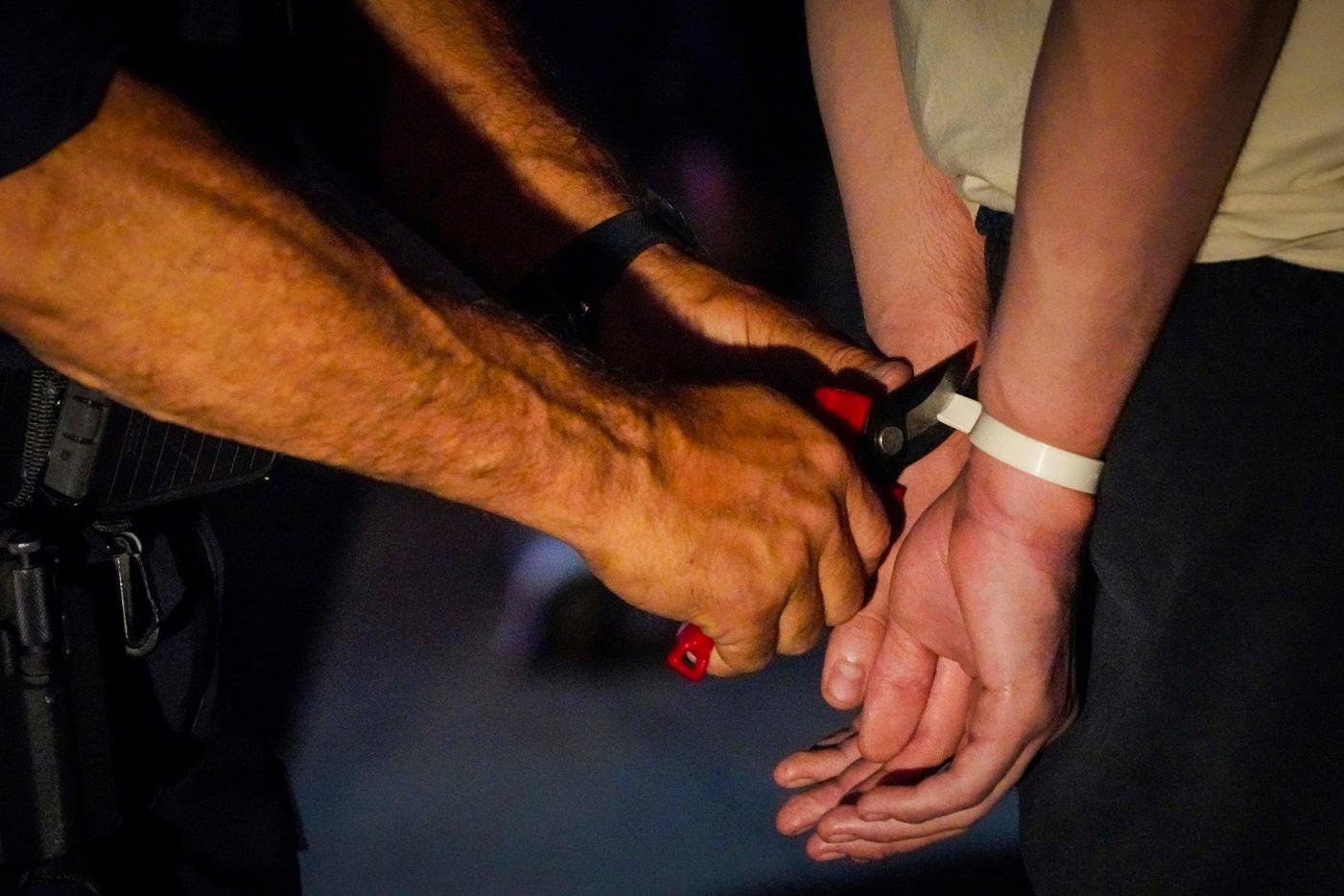 Protesters have their disposable cuffs removed as they are released outside the Frank...