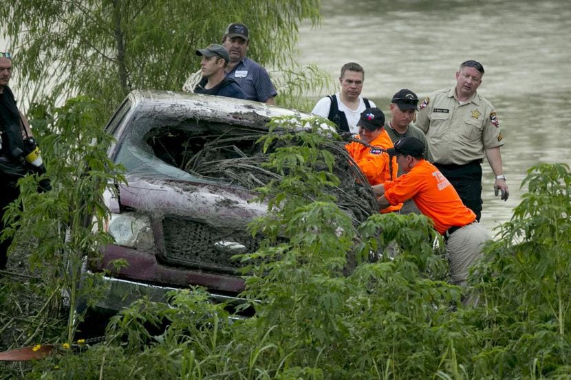 Rescatistas revisan una camioneta arrastrada por el agua de una inundación cerca de un...