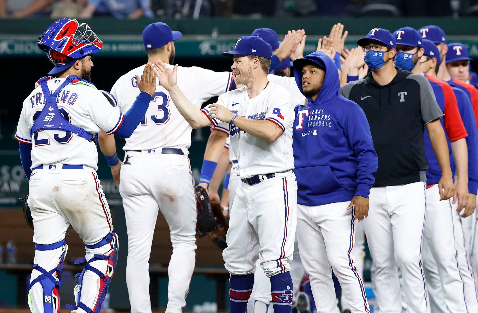 Texas Rangers Brock Holt (center) congratulates catcher Jose Trevino (23) after their win...