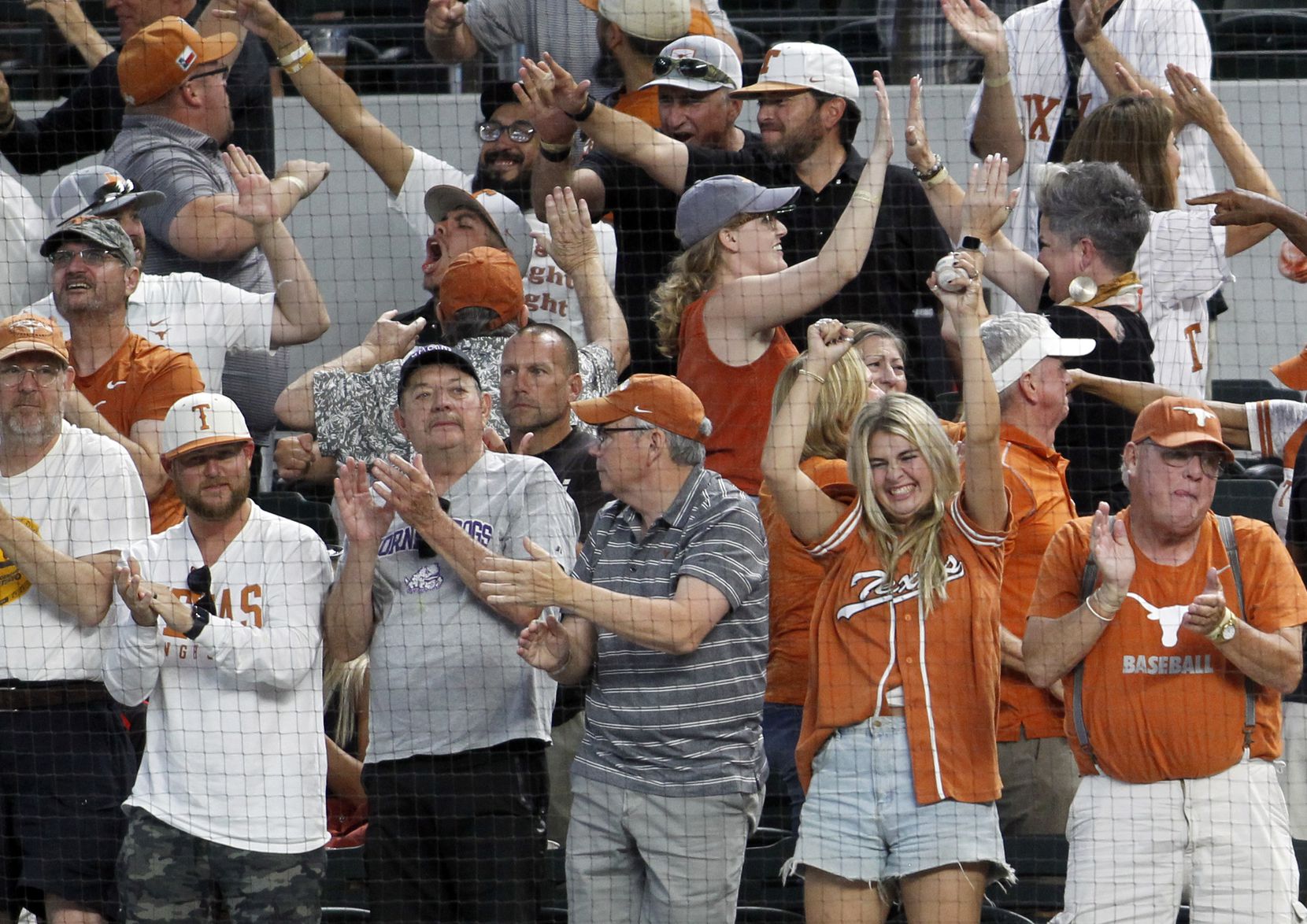 Texas Longhorns fans celebrate in a plethora of ways as they react to a base hit which...