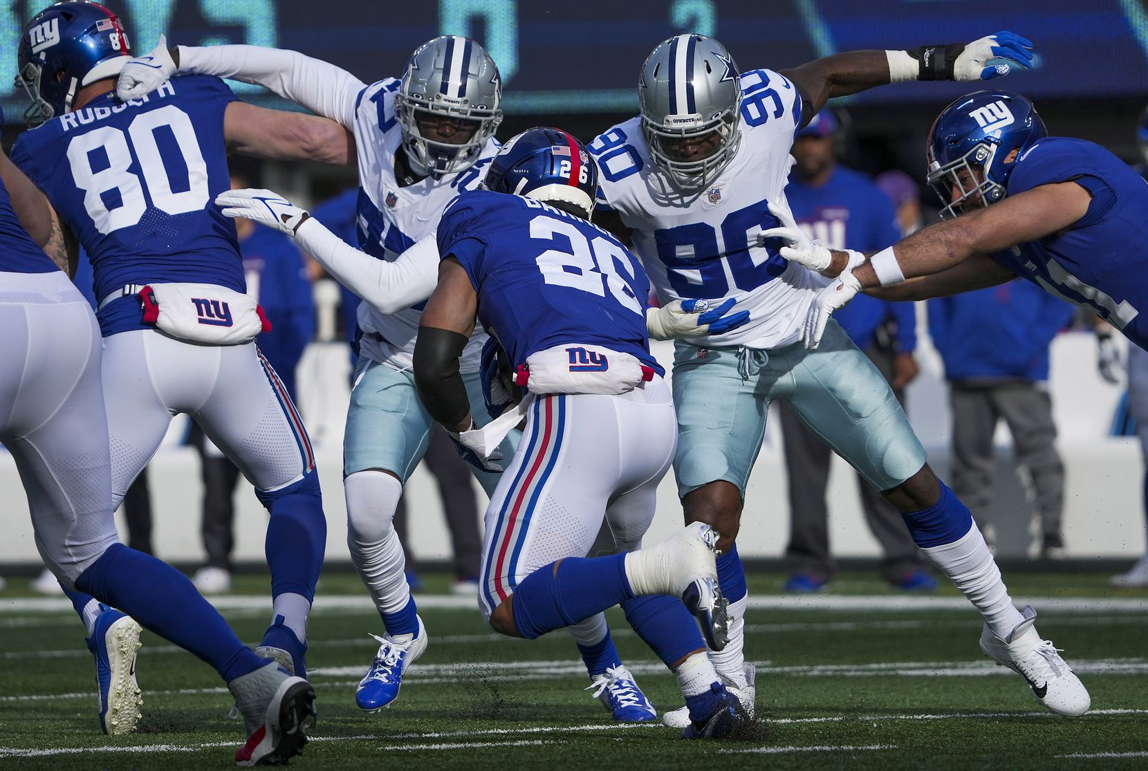 Dallas Cowboys defensive end Demarcus Lawrence (90) and safety Jayron Kearse (27) move in for a tackle on New York Giants running back Saquon Barkley (26) during the first half of an NFL football game on Sunday, Dec. 19, 2021, in East Rutherford, N.J.