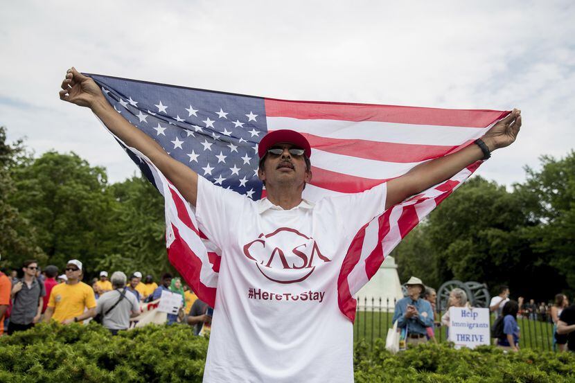 Alejandro Ángeles, de Greenbelt, Maryland, levanta una bandera norteamericana mientras que...