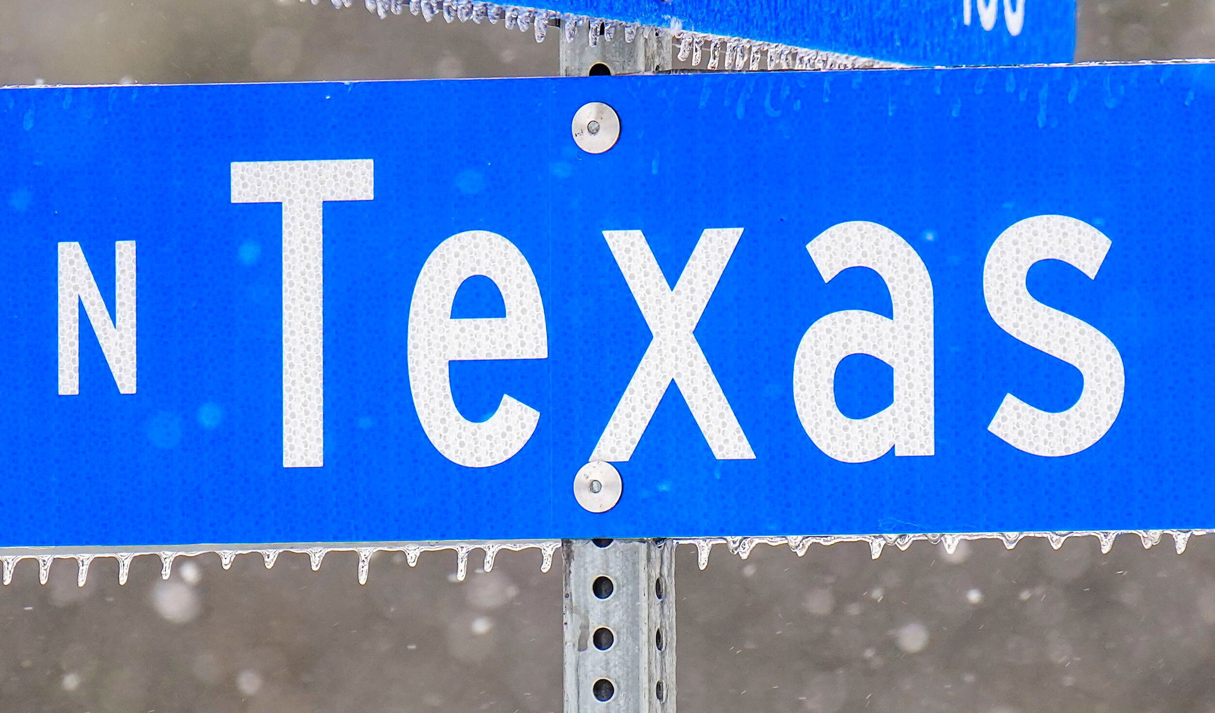 Icicles hang from a street sign in Richardson as snow falls from a winter storm moving into...