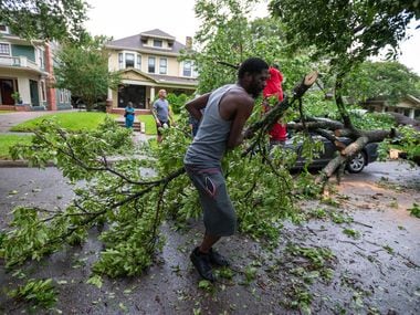 Ricky Neal, 40, drags branches while helping neighbors remove a tree piece by piece from his...