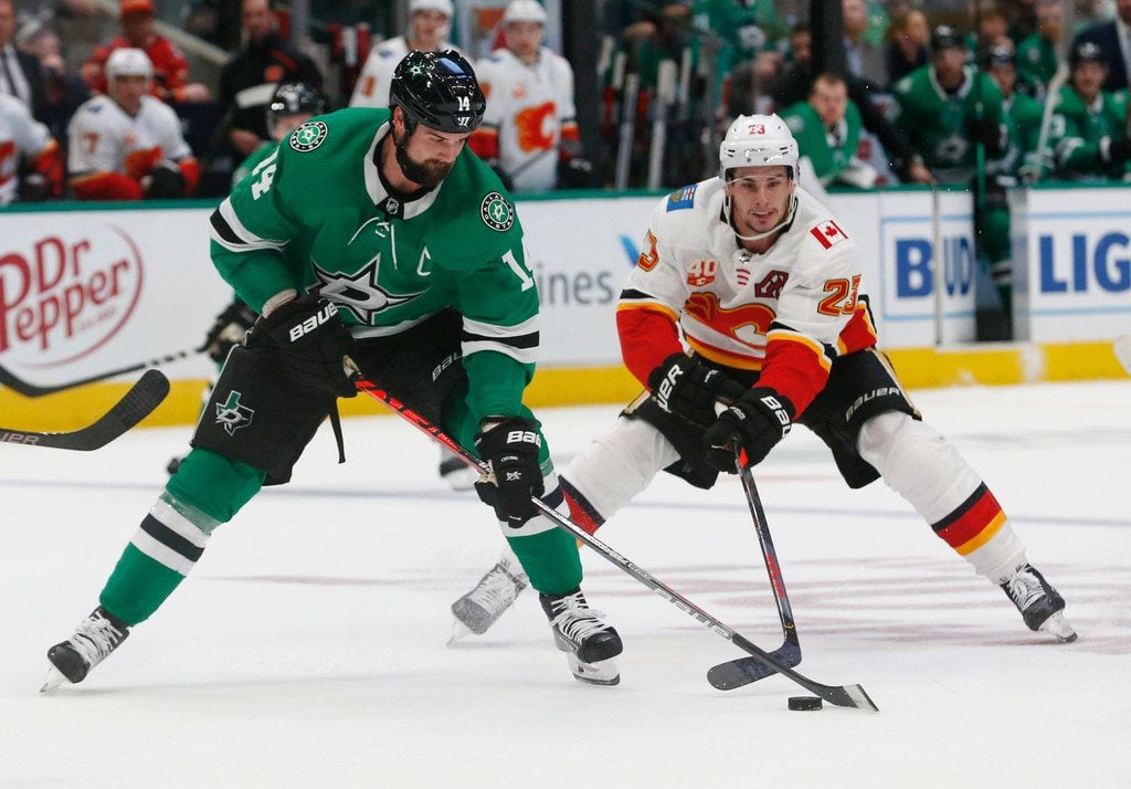 Dallas Stars left wing Jamie Benn (14) and Calgary Flames center Sean Monahan (23) vie for control of the puck during the first period of an NHL hockey game in Dallas, Thursday, Oct. 10, 2019.