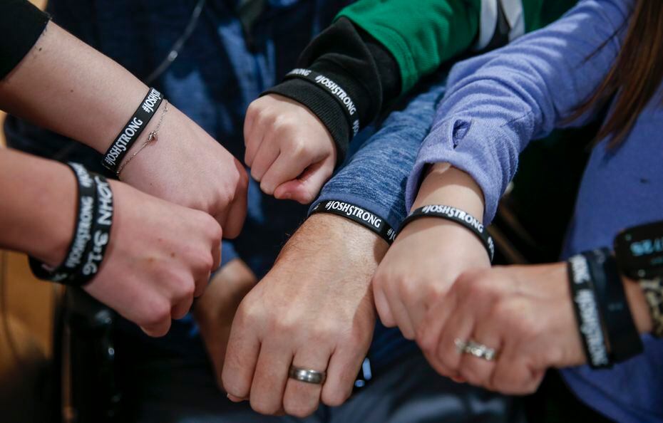 Emily and Josh Welch pose for a photo with their four children while wearing wrist bands a...