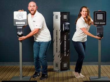 Alex Carroll (left) and Kelsey Carroll ham it up at their offices on Monday, May 18, 2020, in Irving. Due to the COVID-19 pandemic, the husband and wife team transitioned their party planning business, Toss Up Events, to providing hand sanitizer machines as a new business called Stand Up Stations. (Smiley N. Pool/The Dallas Morning News)