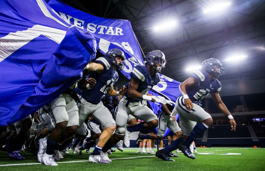 Frisco Lone Star football players run on the field before a District 5-5A Division I high...