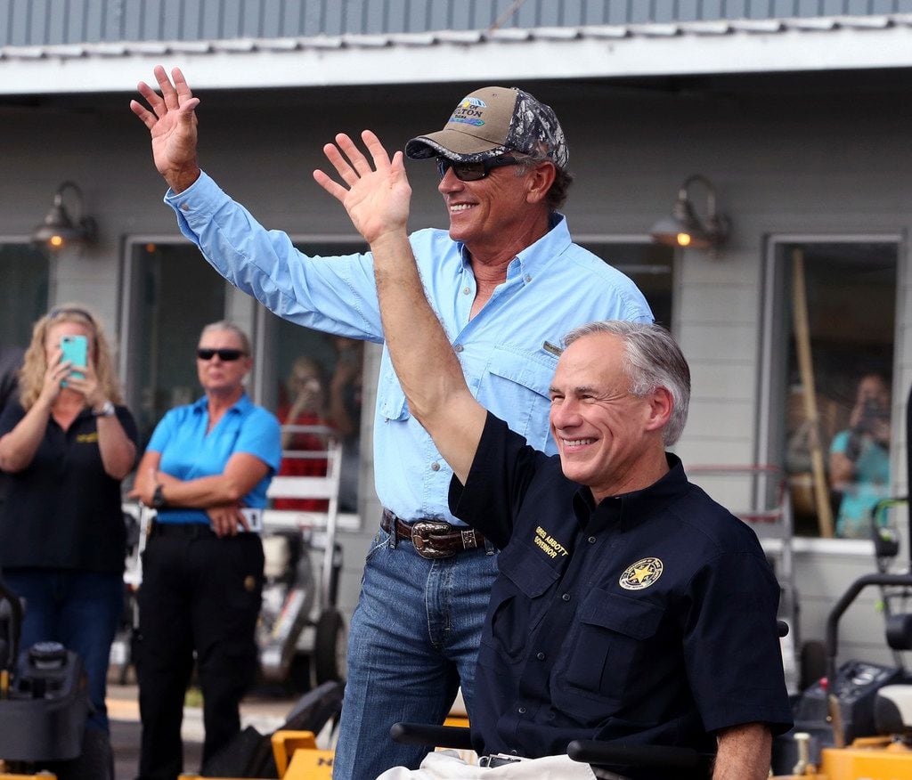 George Strait (left) and Texas Gov. Greg Abbott wave to the crowd in Rockport during a visit...
