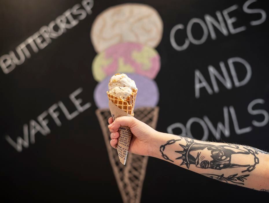 Shop keeper Ellyn McDonald holds a waffle cone of Gooey Butter Cake, top, and Salted Peanut...