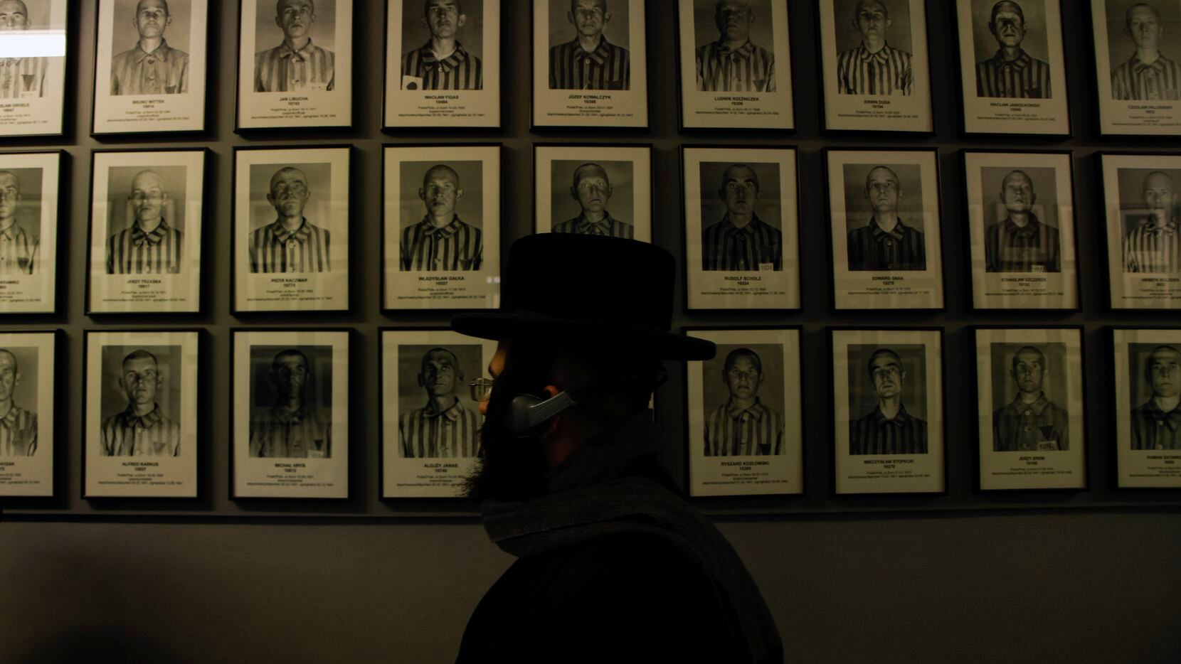 An orthodox Jew walks past the portraits of victims at the former Nazi German concentration...