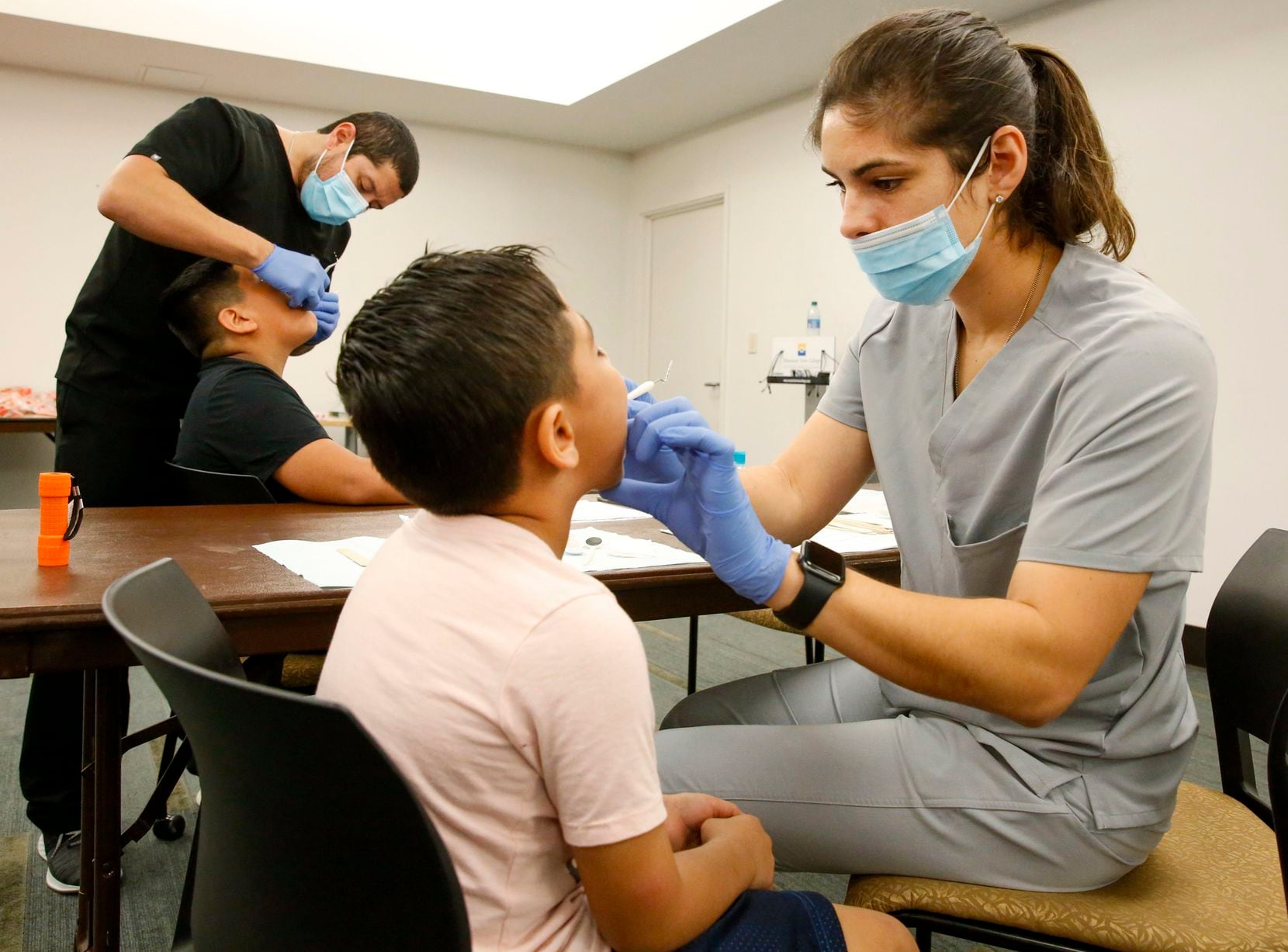 12-year-old Roberto Rosales, left and 6-year-old Victor Rosales get their teeth checked by Marcus Ruis DDS and Alina Garciamendez DDS during a free health fair coordinated by the Mexican Consulate at Mountain View College in Dallas Saturday October 21, 2019.