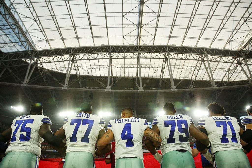 Dallas Cowboys quarterback Dak Prescott (4) locks arms with teammates during the playing of...