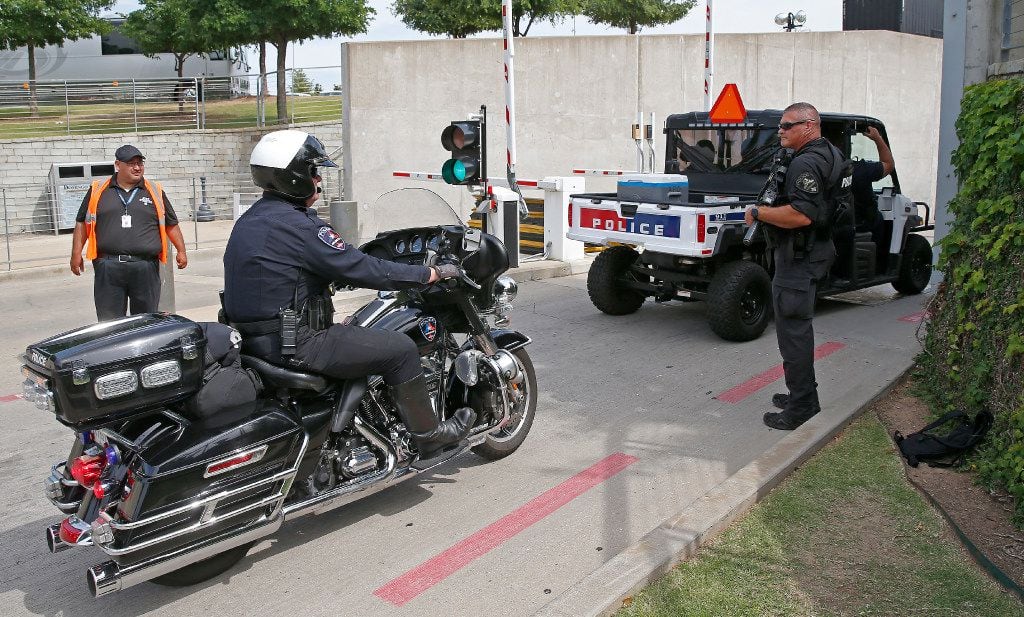 Law enforcement officers enter the AT&T Stadium as an Arlington police officer guards the...
