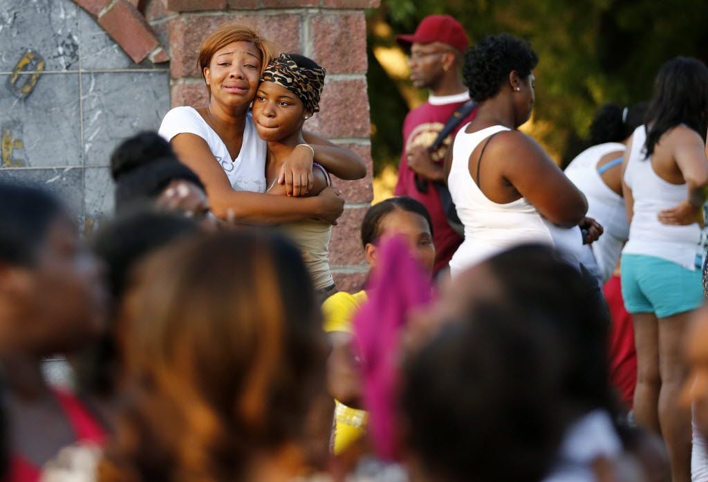 Staneccia Richardson (left), a cousin of shooting victim James Harper, gets comforted by her...