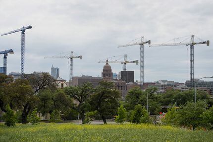 The Texas State Capitol building stands beyond construction cranes at the University of...