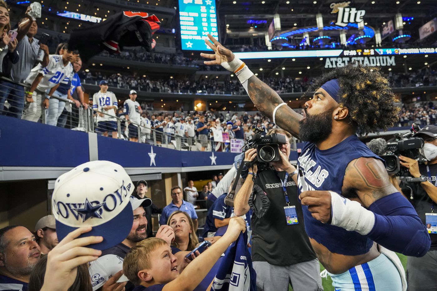 Dallas Cowboys running back Ezekiel Elliott tosses a jersey back to a fan after autographing it as he leaves the field following a victory over the Washington Football Team in an NFL football game at AT&T Stadium on Sunday, Dec. 26, 2021, in Arlington. The Cowboys won the game 56-14.