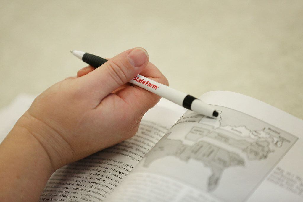 A student holds a pen while attending a college history class. Contributor Kevin Kruger...