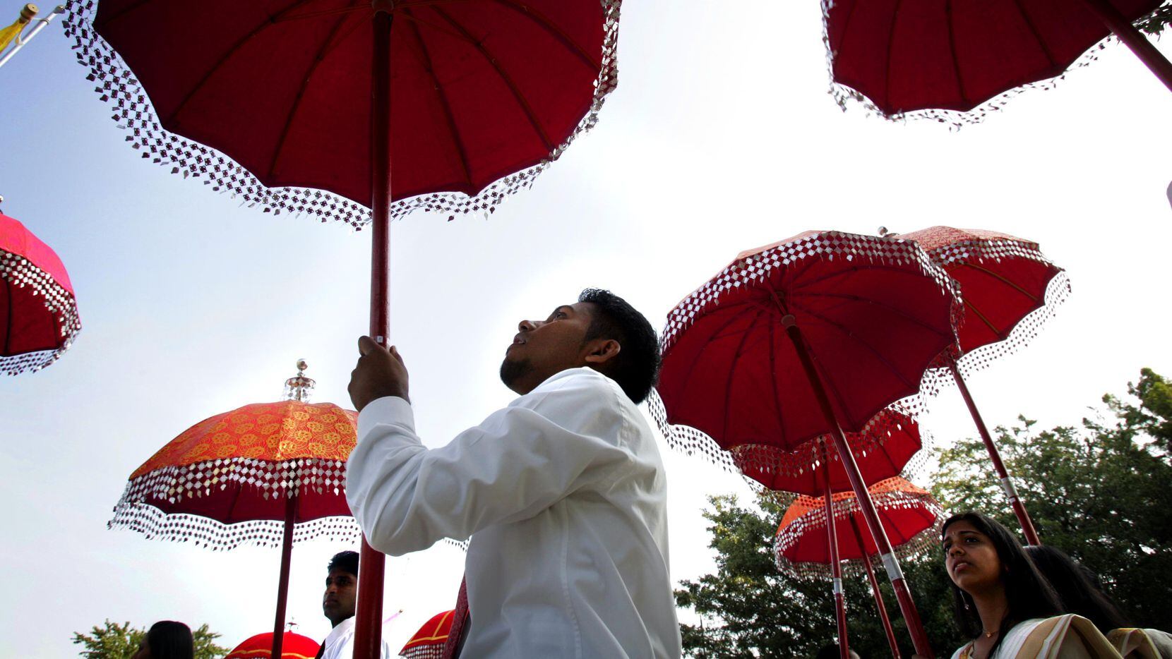 Tharun Mathai, of Houston, holds onto his  festive umbrella during a procession, at the...