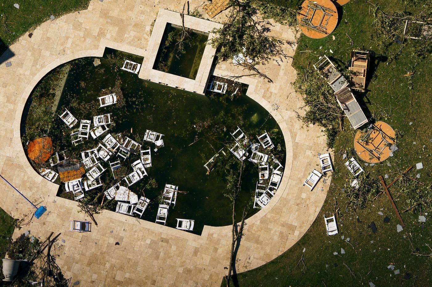Chairs float in a backyard pool with debris from tornado damage near Walnut HIll Lane and...