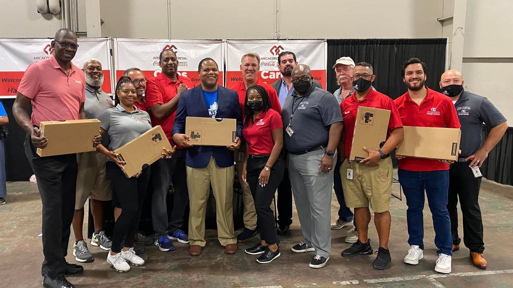 A group of Coca-Cola Southwest Beverages volunteers in polo shirts hold boxes.