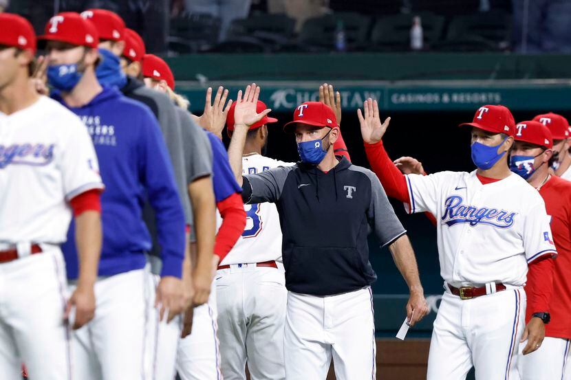 El mánager de los Rangers de Texas, Chris Woodward (centro), saluda a sus jugadores tras...