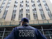 A New York State court officer stands guard outside the District Attorney's office,...
