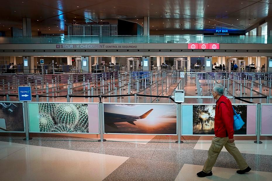 A man wearing a face mask walk past the otherwise empty security lines at Dallas Love Field on Tuesday, April 14, 2020, in Dallas.  (Smiley N. Pool/The Dallas Morning News)