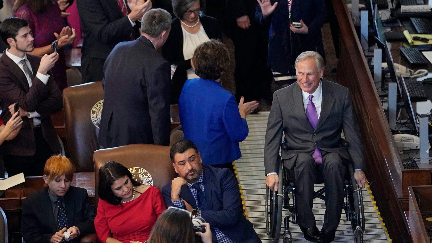 Texas Gov. Greg Abbott, right, arrives in the House Chamber at the Texas Capitol during the...