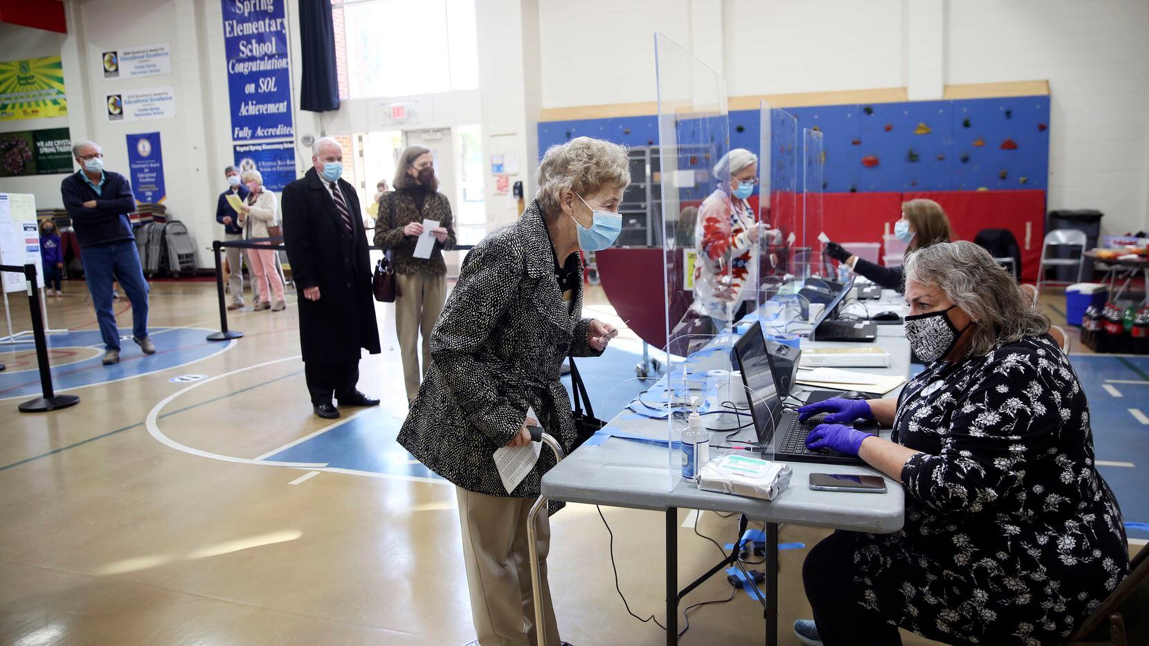 Betty Holland, de 76 años, a la izquierda, se registra para votar con la funcionaria...