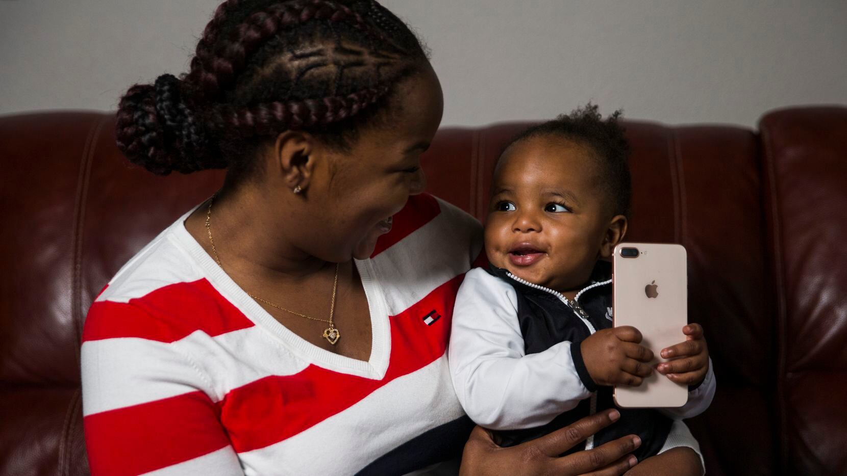 Ariel Murphy lets her 18-month-old son, Kairo, play with her cellphone at their home in...