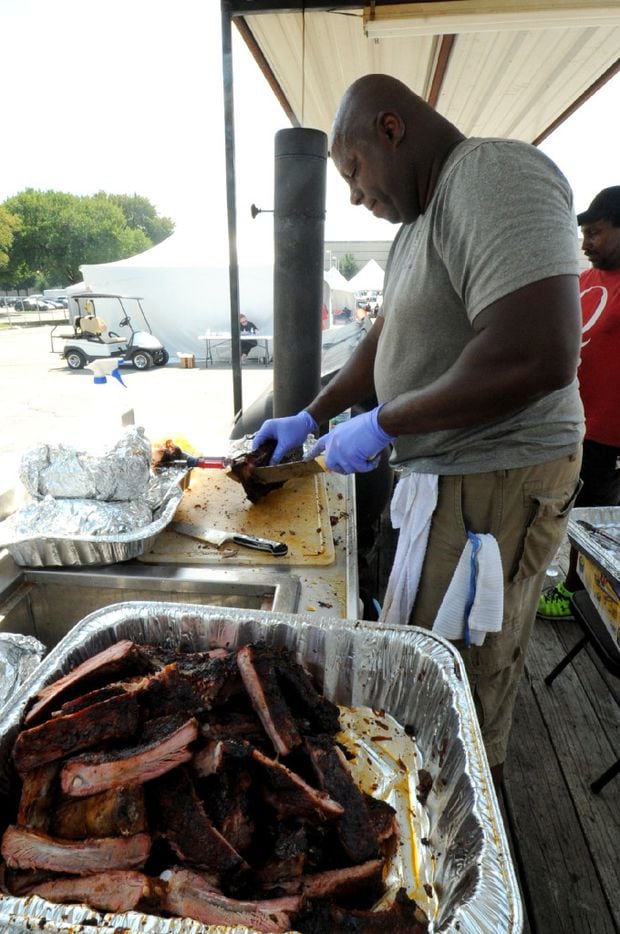 Milton Williams of Dallas Fire Department slices smoked ribs for patrons at Battle of the...