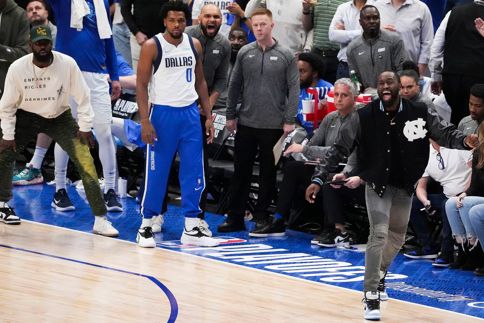 Dallas Mavericks guard Theo Pinson (in black jacket) steps out on the court in celebration...