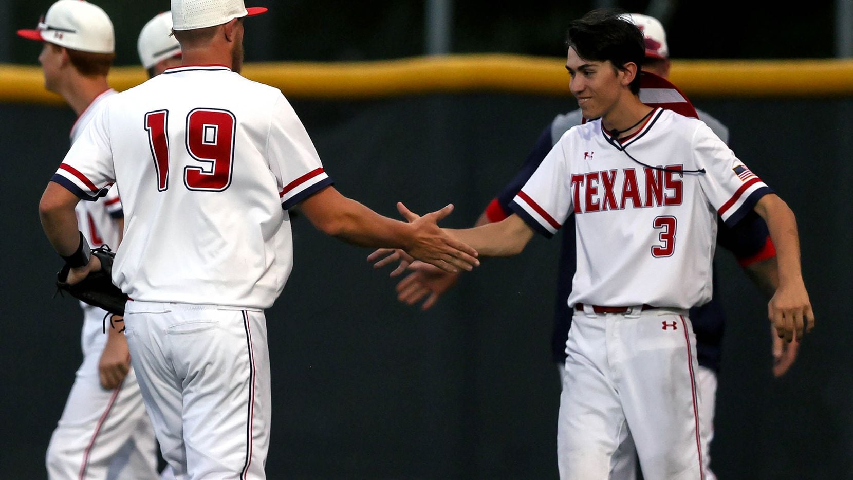 Justin Northwest starting pitcher Carter Ramussen (19) is greeted by Michael Boulet (3)...